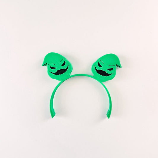 Green headband with cartoonish face design on a white background