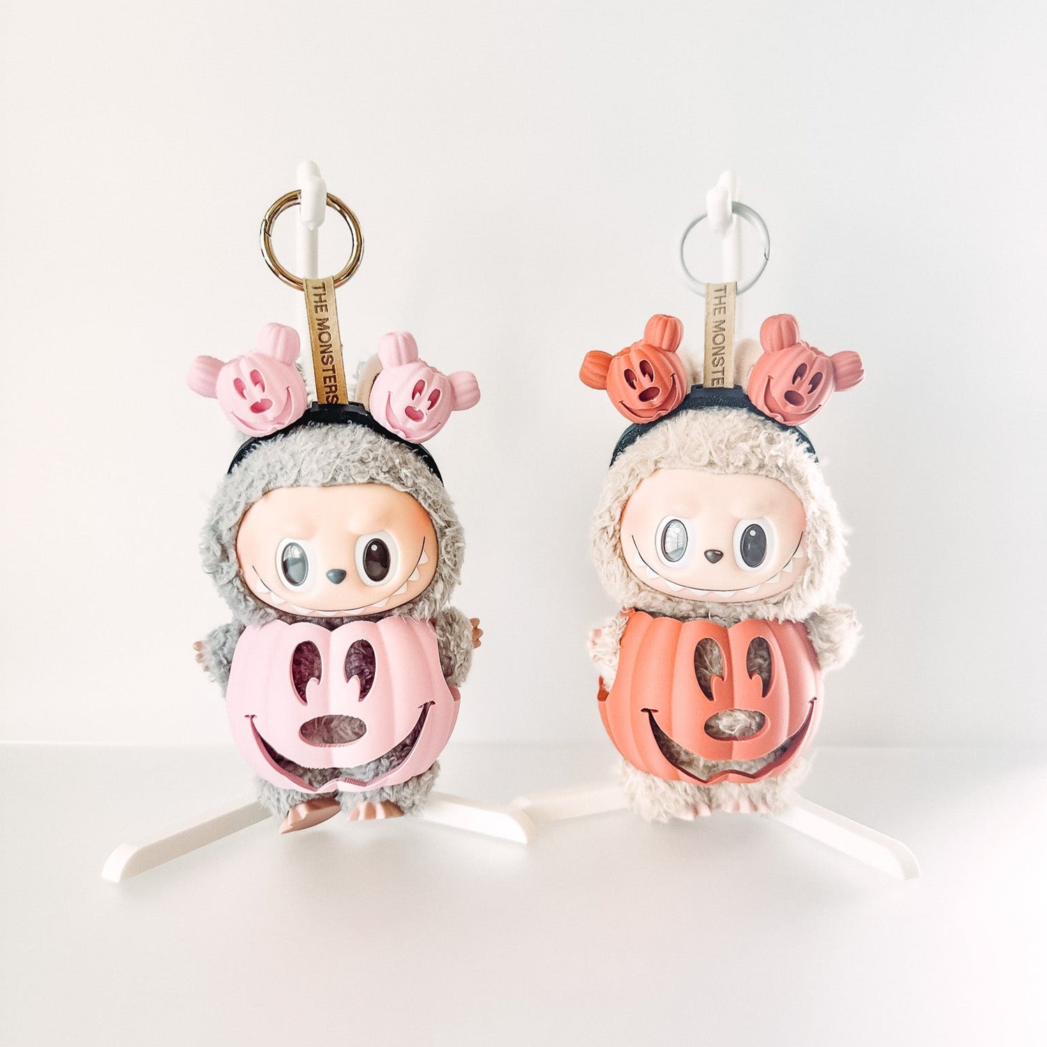 Two plush keychains shaped like cartoon characters with pink hair and black hair on a white background.