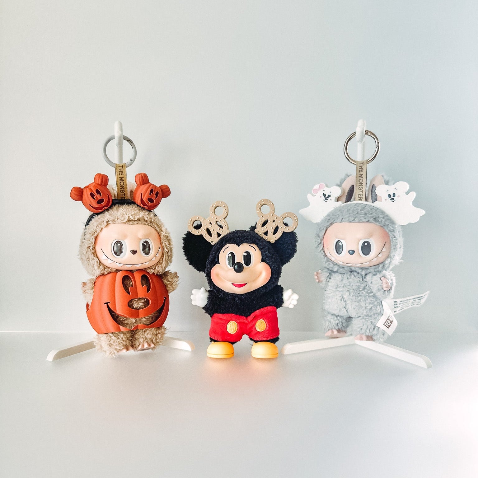 Three cartoon character keychains in Halloween costumes on a white background