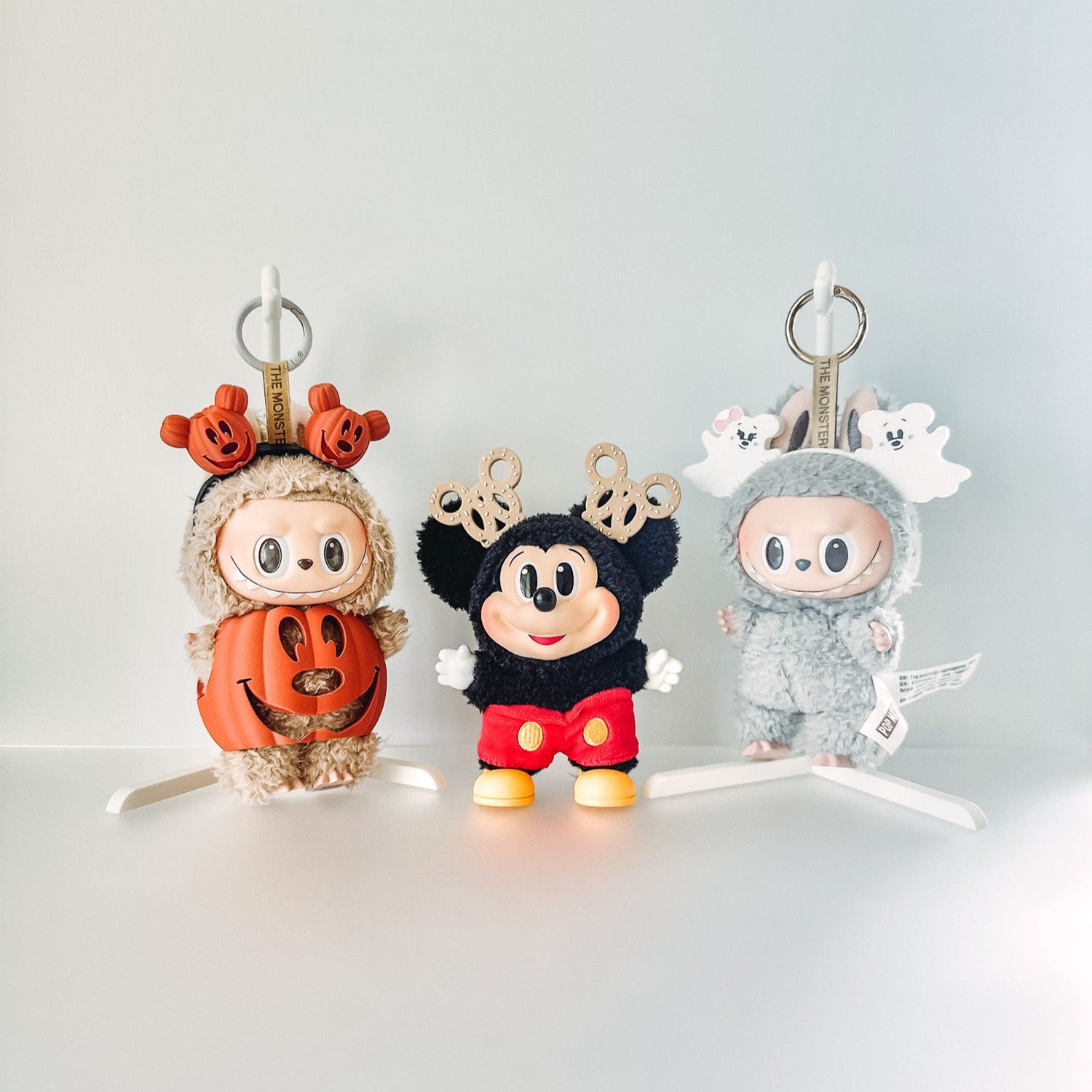 Three cartoon character keychains in Halloween costumes on a white background