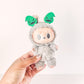 Plush toy with green ears held by a hand on a white background