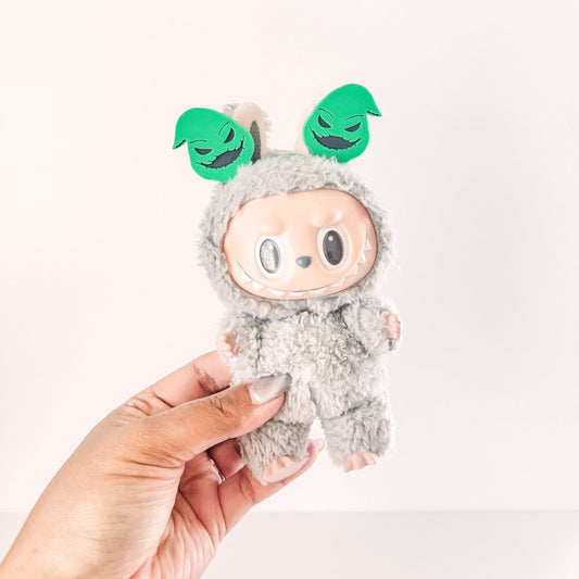 Plush toy with green ears held by a hand on a white background