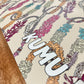 Decorative mat with floral patterns and 'KUMU' branding on a wooden surface.