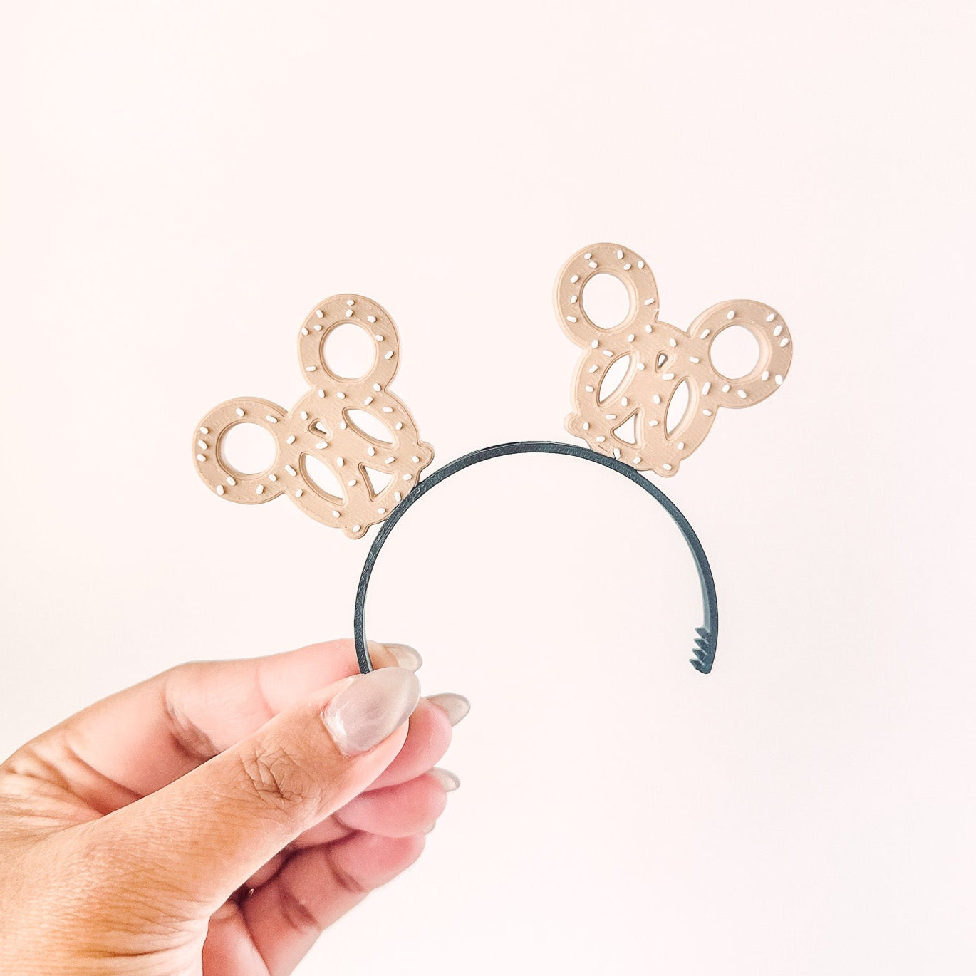 Hand holding a headband with decorative bunny ears on a white background