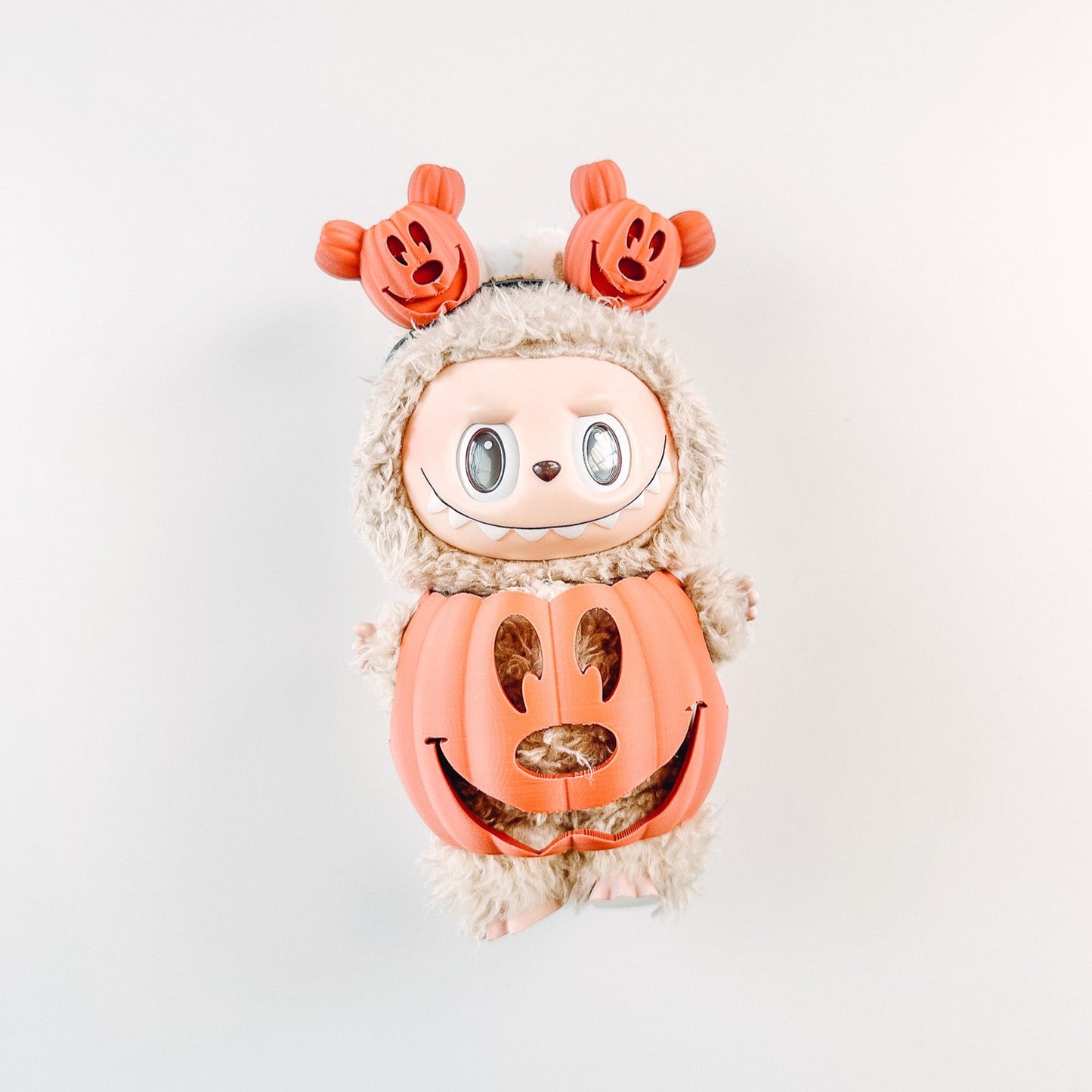 Halloween-themed plush toy with pumpkin face and leaf hat on a white background